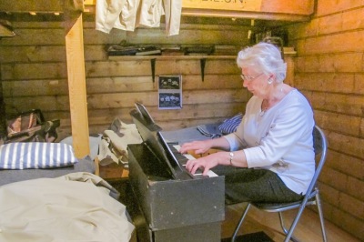Phillipa playing the organ in the replica hut. 