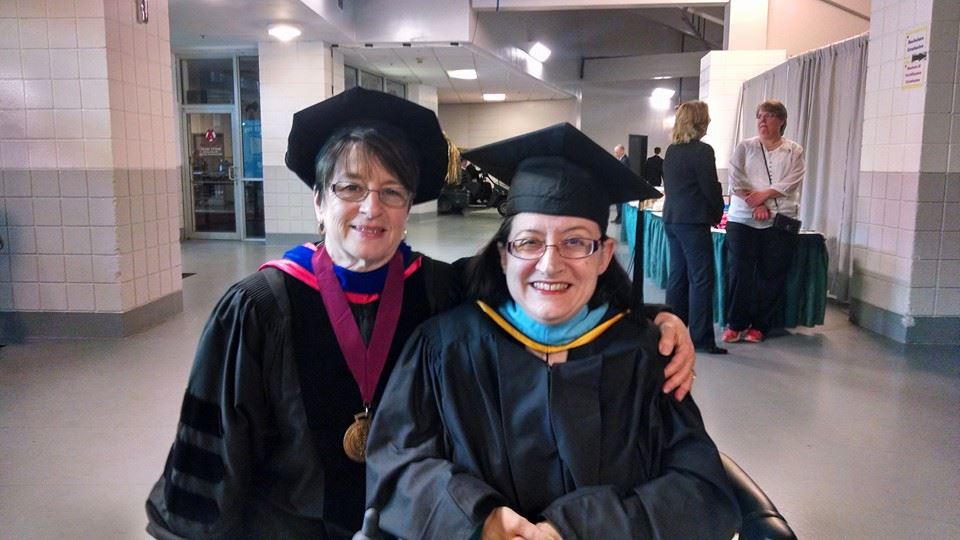 Photo of two women wearing academic cap and gown.